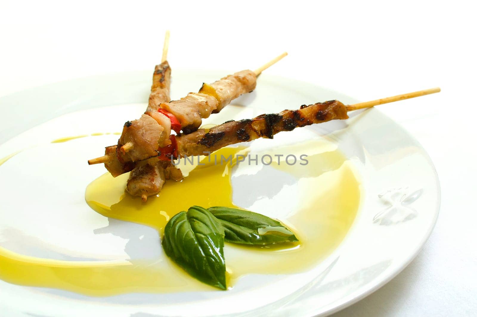 A dish with three little skewers and olive oil garnish
