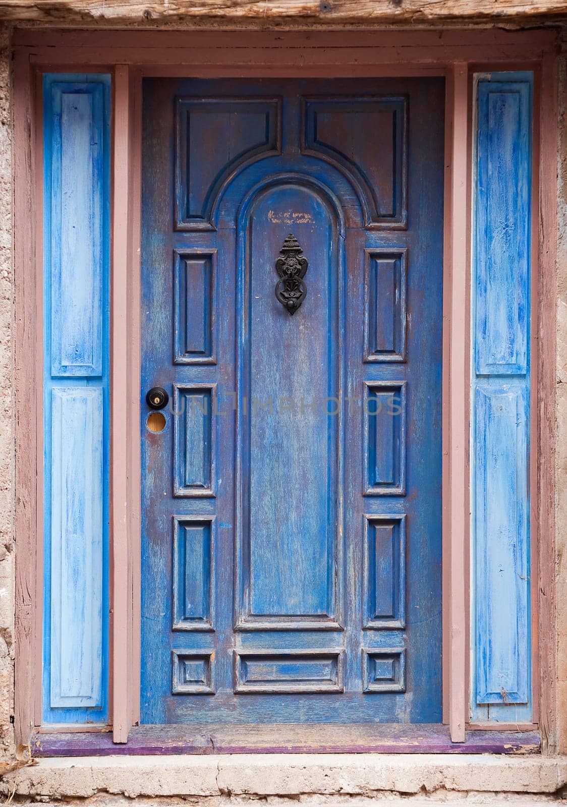 Old peeling blue door with metal knocker