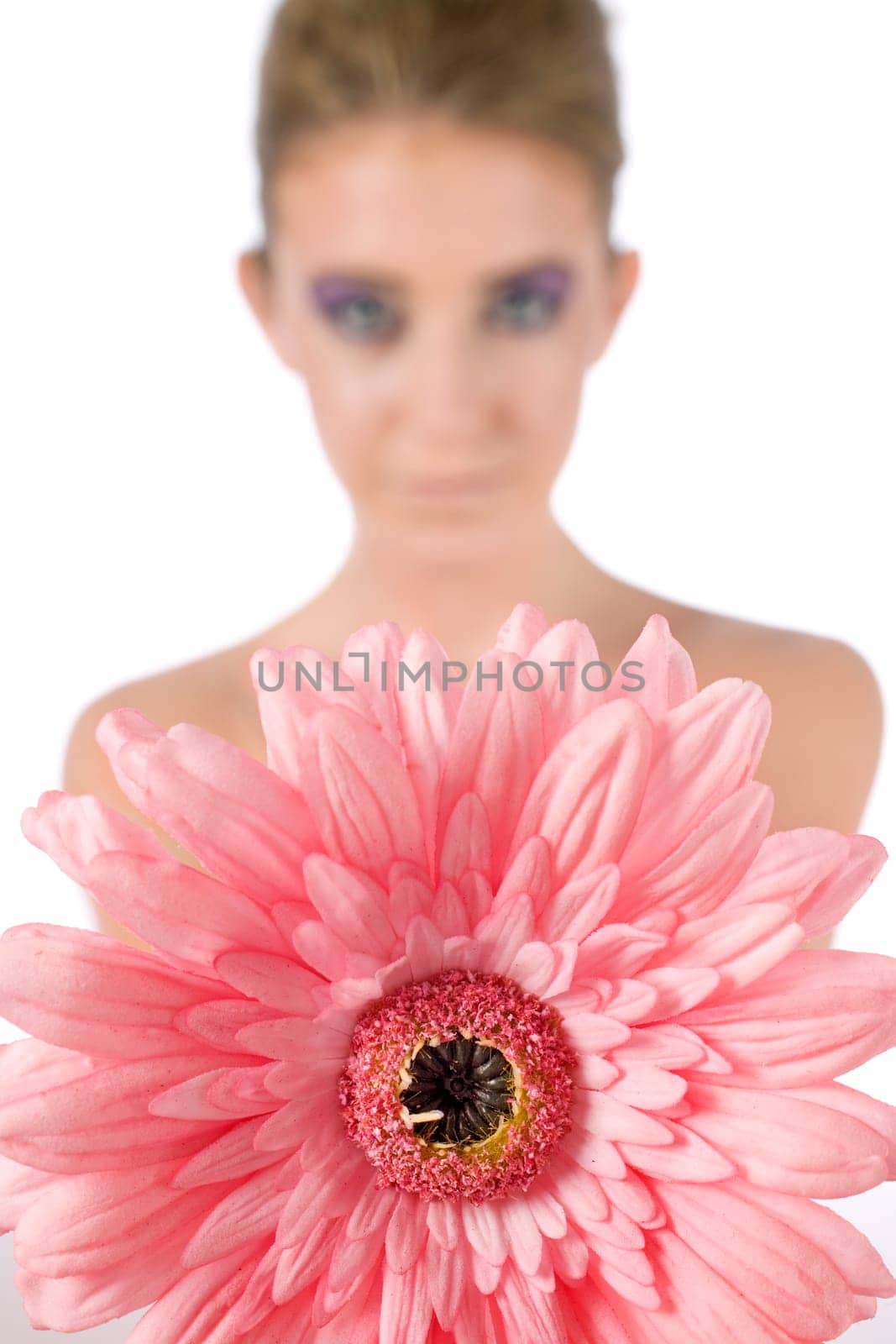 Female model holding a pink flower with strong eye makeup, on a white background