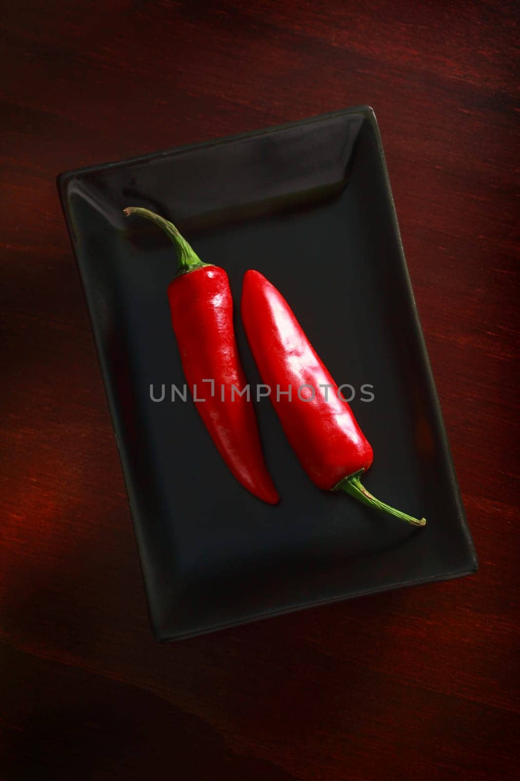 Still life. 2 chillies on a black