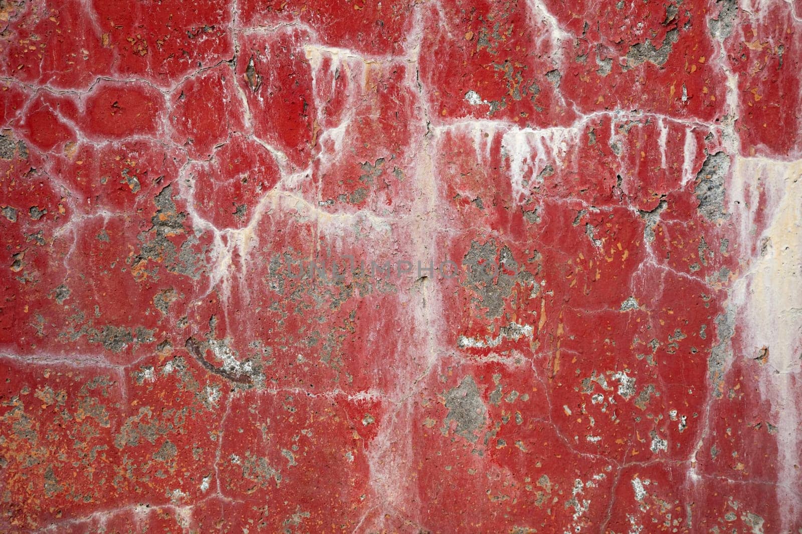 Red dirty cracked concrete wall background with stains