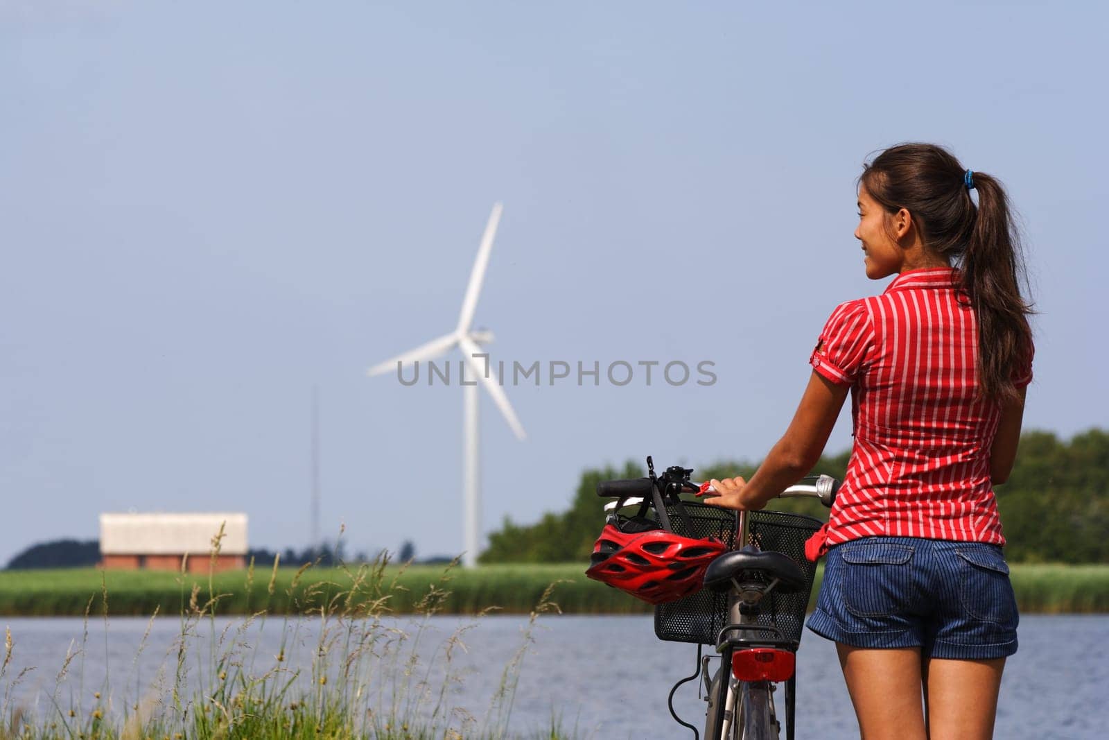 Woman relaxing and enjoying the sun on a bike trip in the countryside of Jutland, Denmark Windmill in the background.