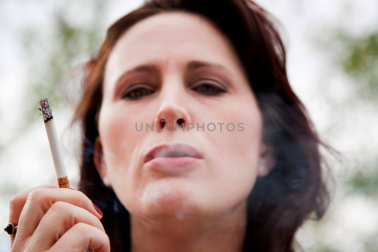 Young woman smoking in front of a tree