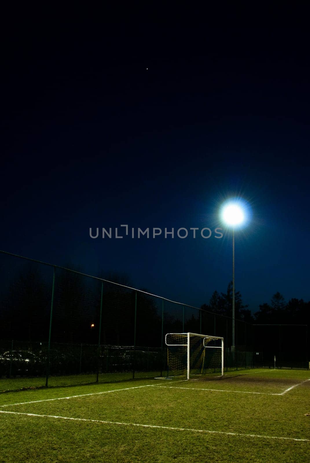 football field lit at night with goal and spot