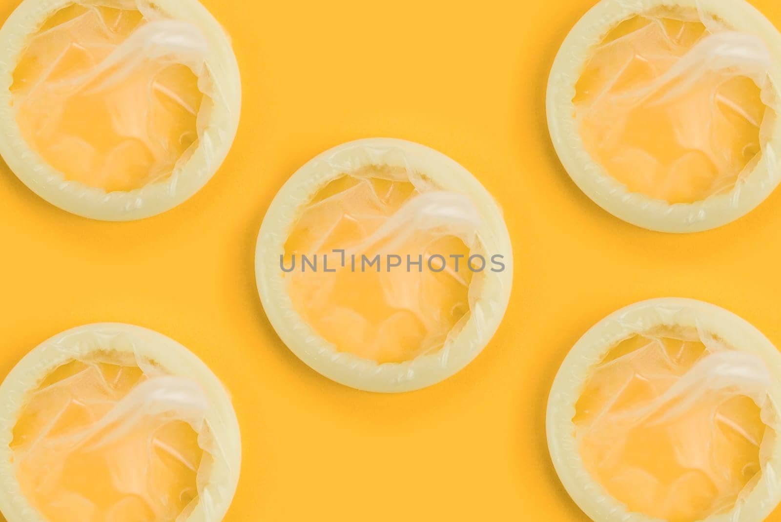 Set of yellow condoms on orange background