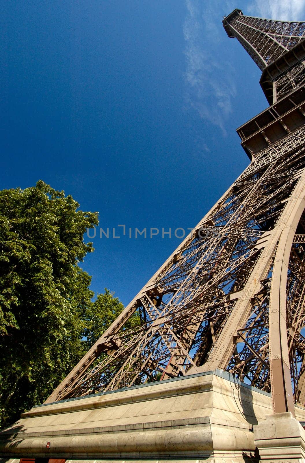 Unusual perspective of the Eiffel Tower, taken with a wide angle lens, with a blue sky background