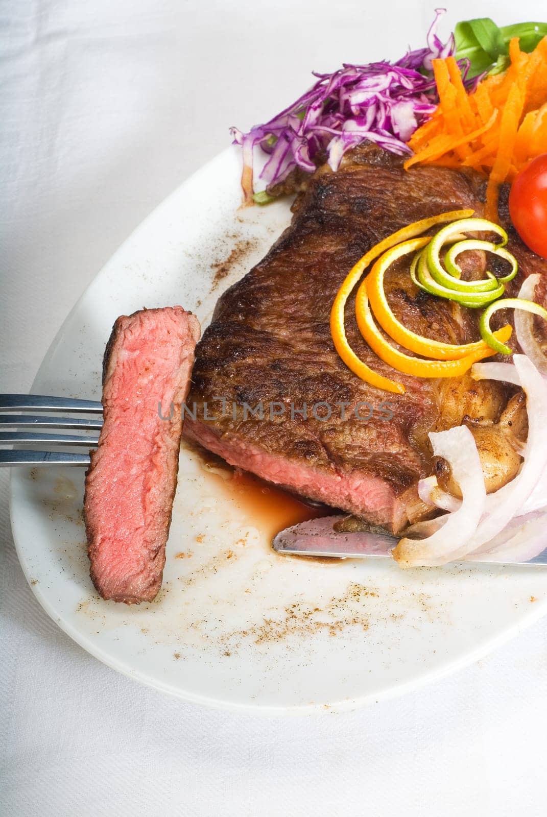 fresh juicy beef ribeye steak sliced ,with lemon and orange peel on top  and vegetable beside