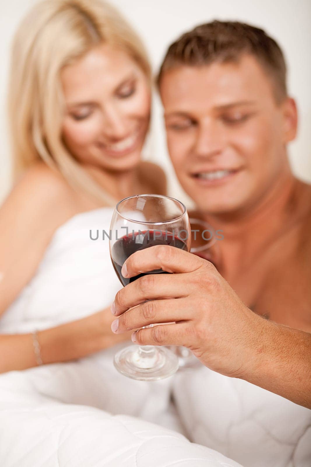 Young couple toasting champagne in bed