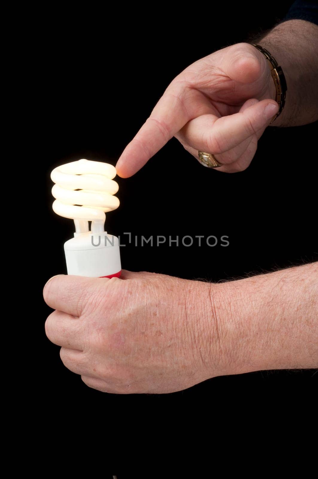 Man holding a pigtail flourescent light bulb which is alight in one hand and pointing at it with the other hand suggesting this is the future