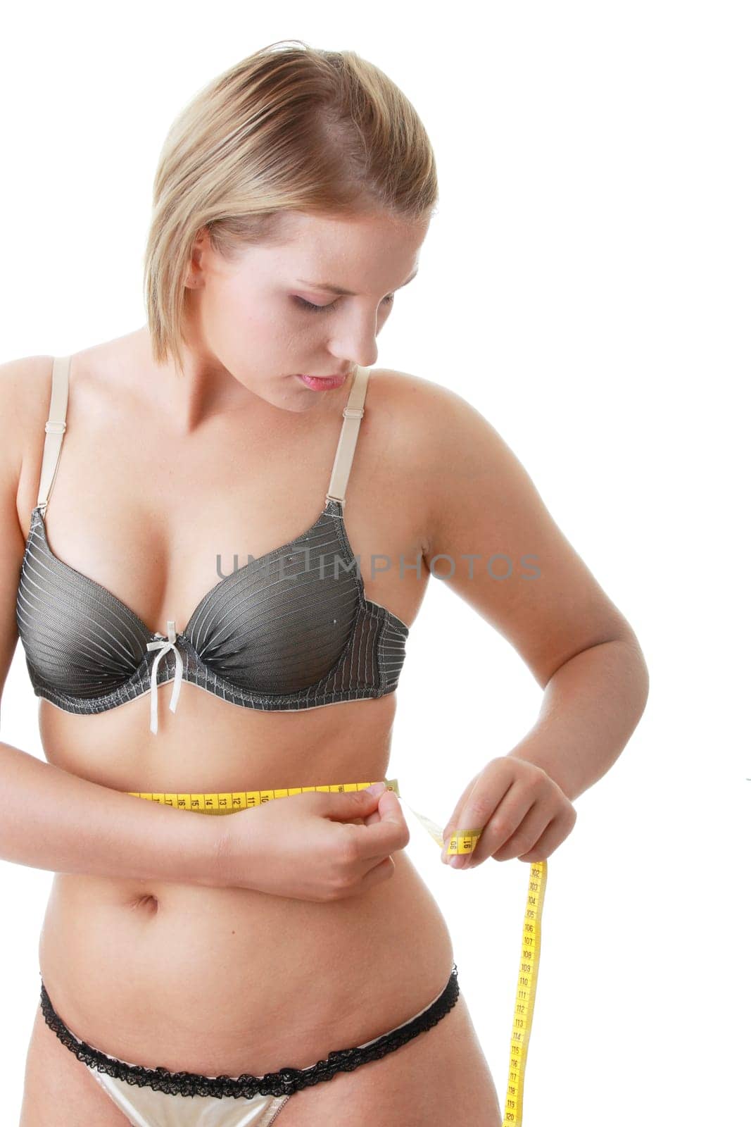 A little bit fat young woman mesuring her body isolated on white background
