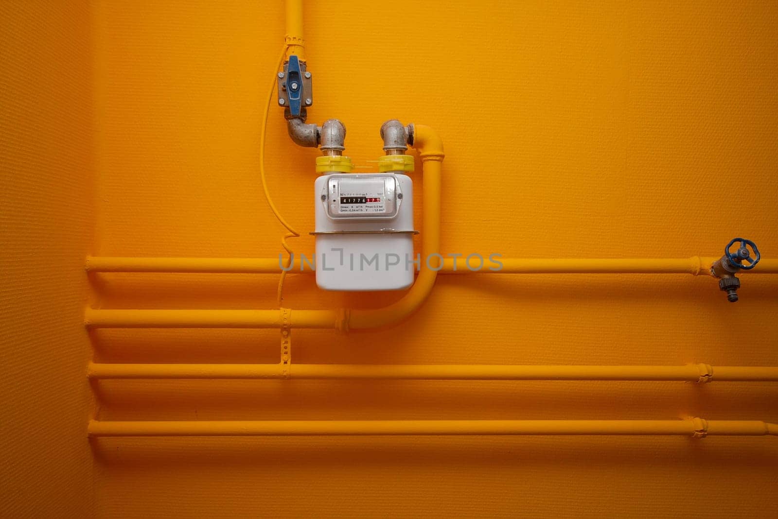 Pipes and gas-meter on orange wall