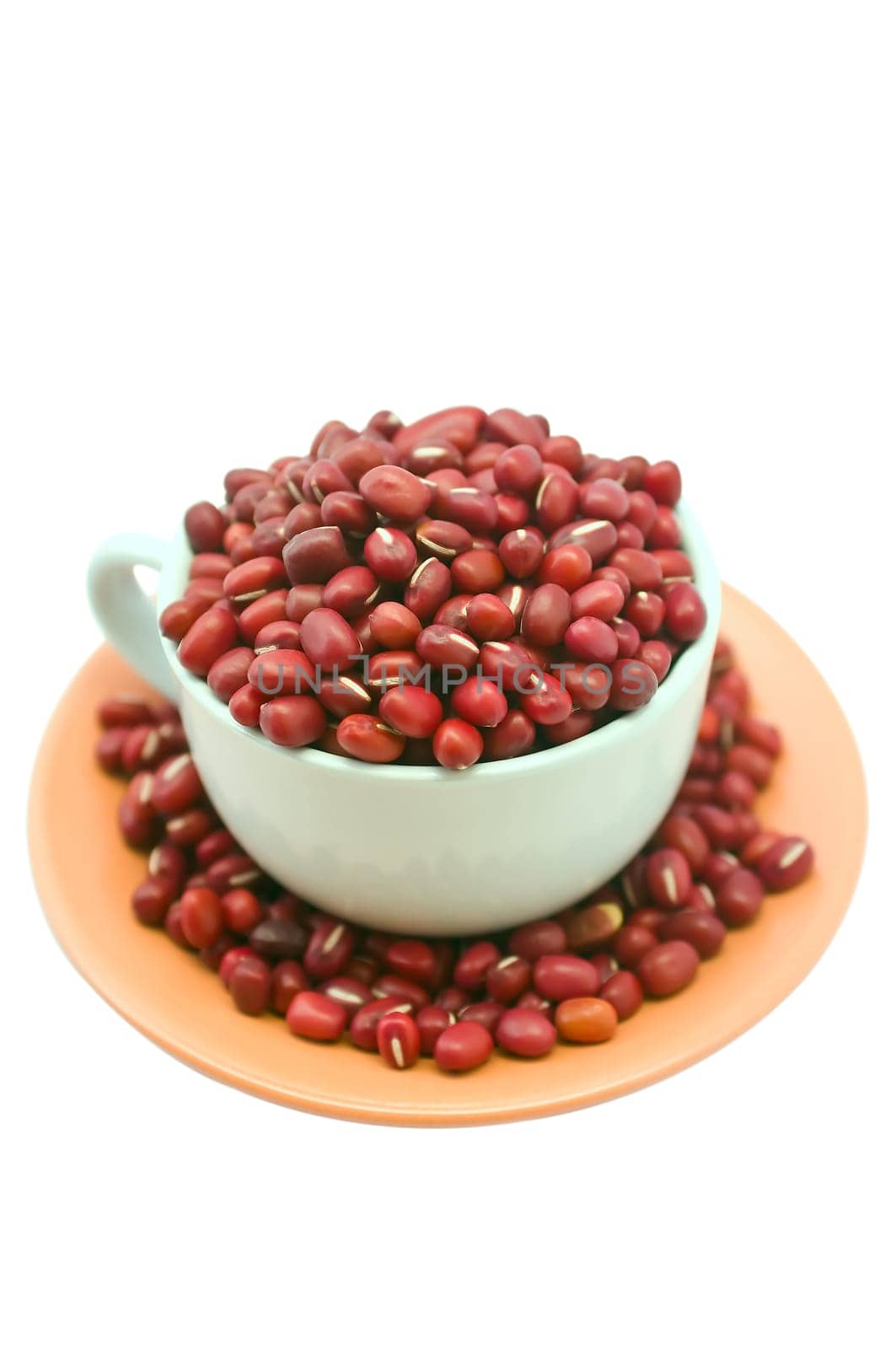 A white porcelain cup brimming with dried adzuki (red) beans, with a pale red saucer.