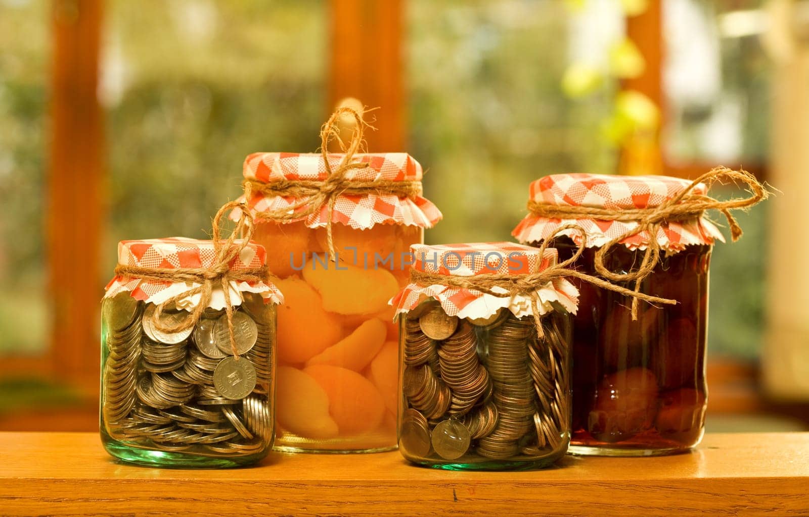 Save when you have plenty - money saving concept with canned fruits and money in glass jars