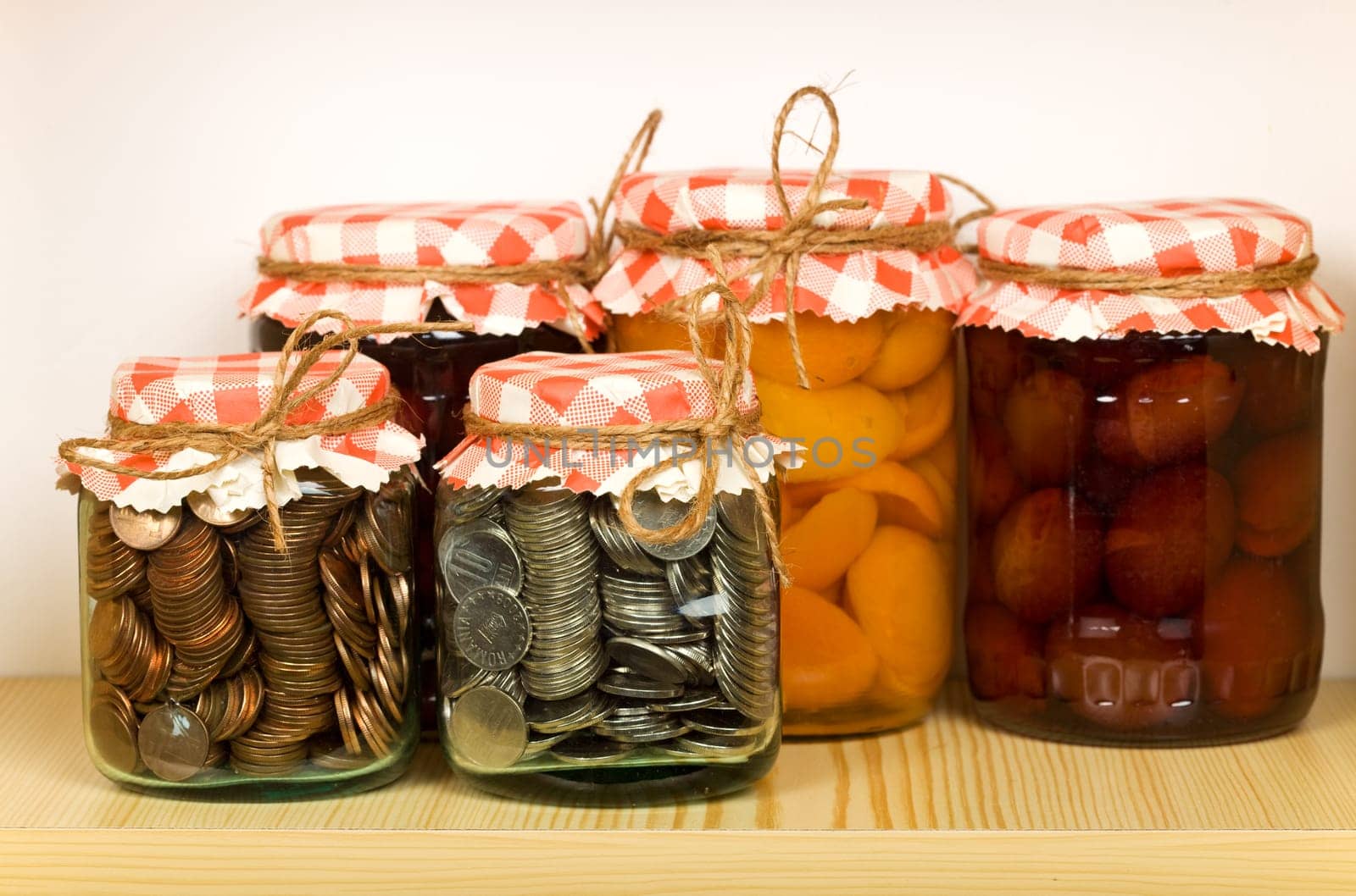 Savings concept with money canned in glass jars on the shelf