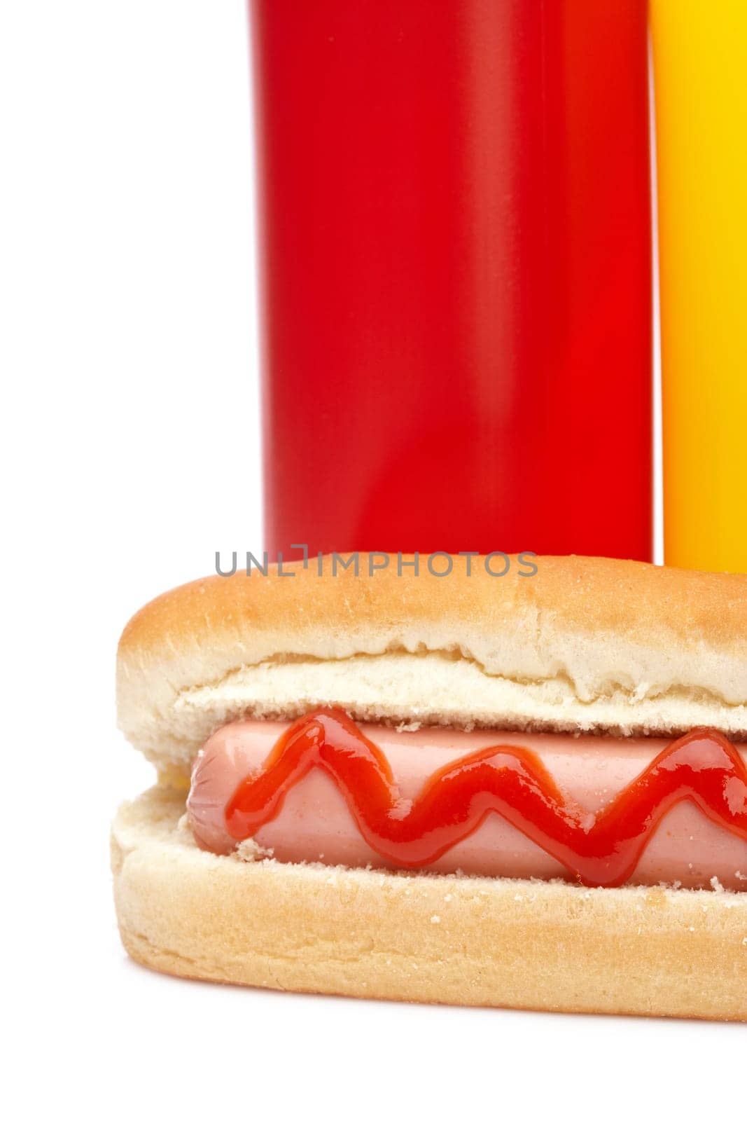 A hot dog with ketchup and mustard bottles isolated on white background