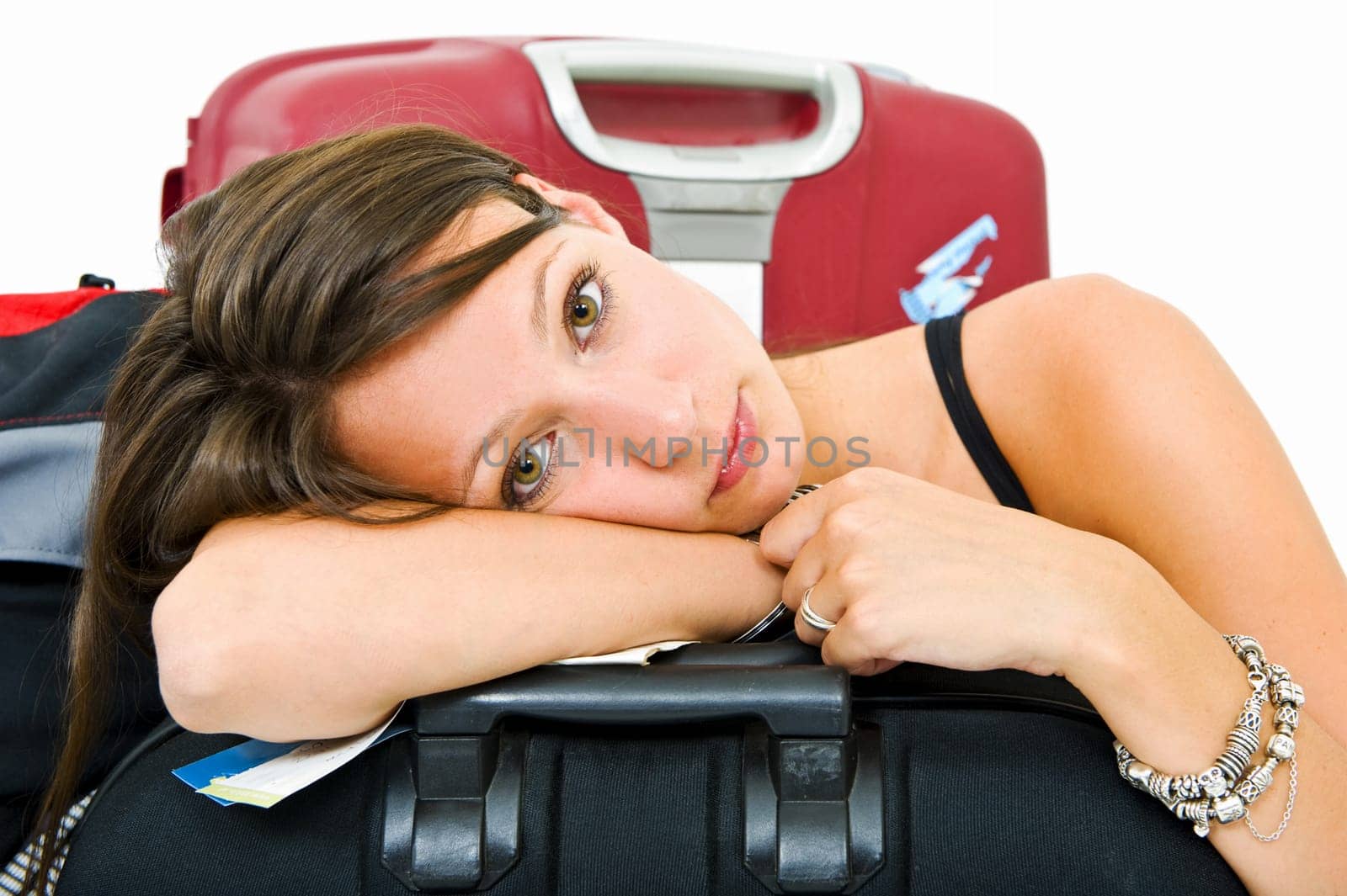 Young woman, resting her head on a suitcase, weary from travelling