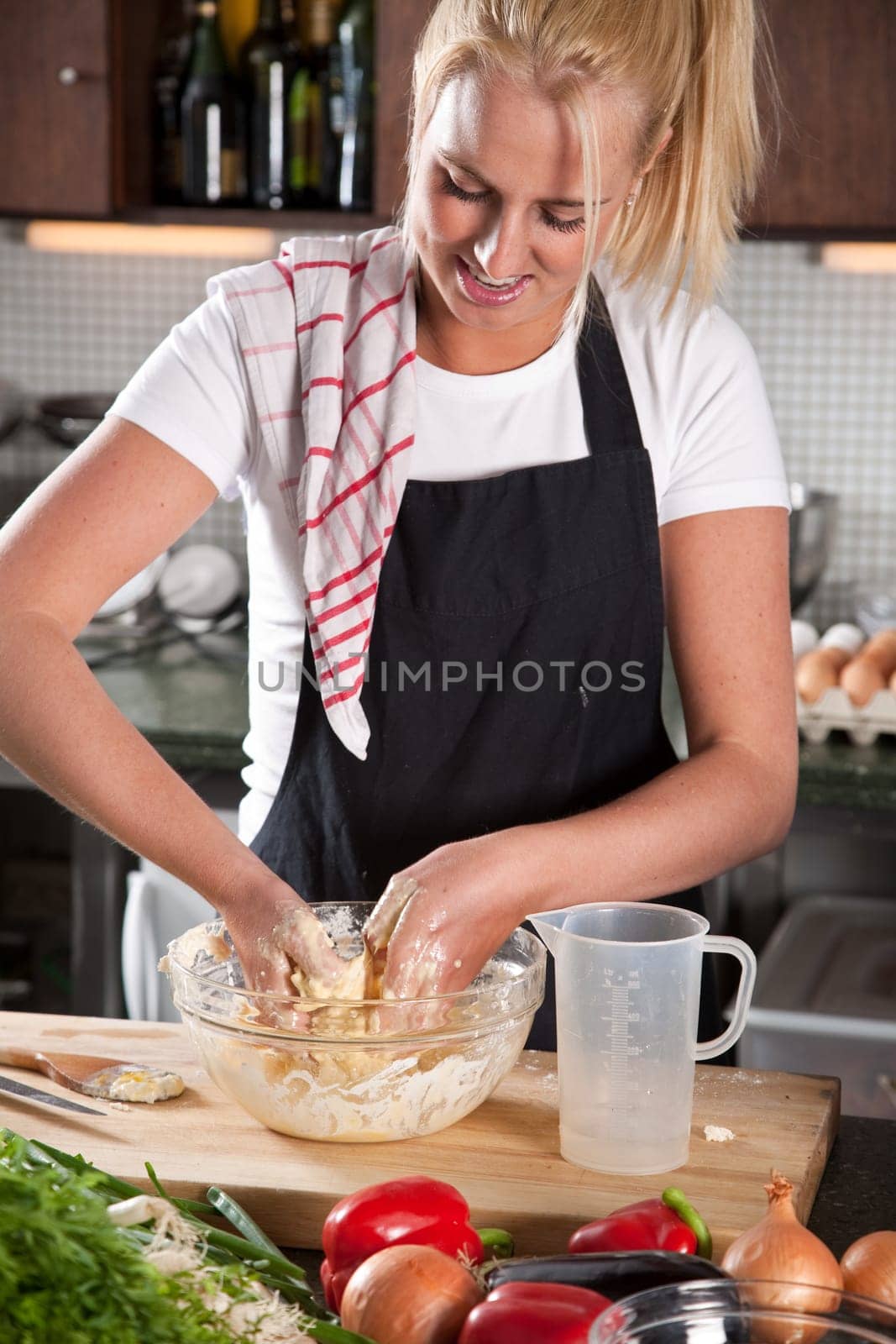 Pretty blond woman kneading the dough in the kitchen