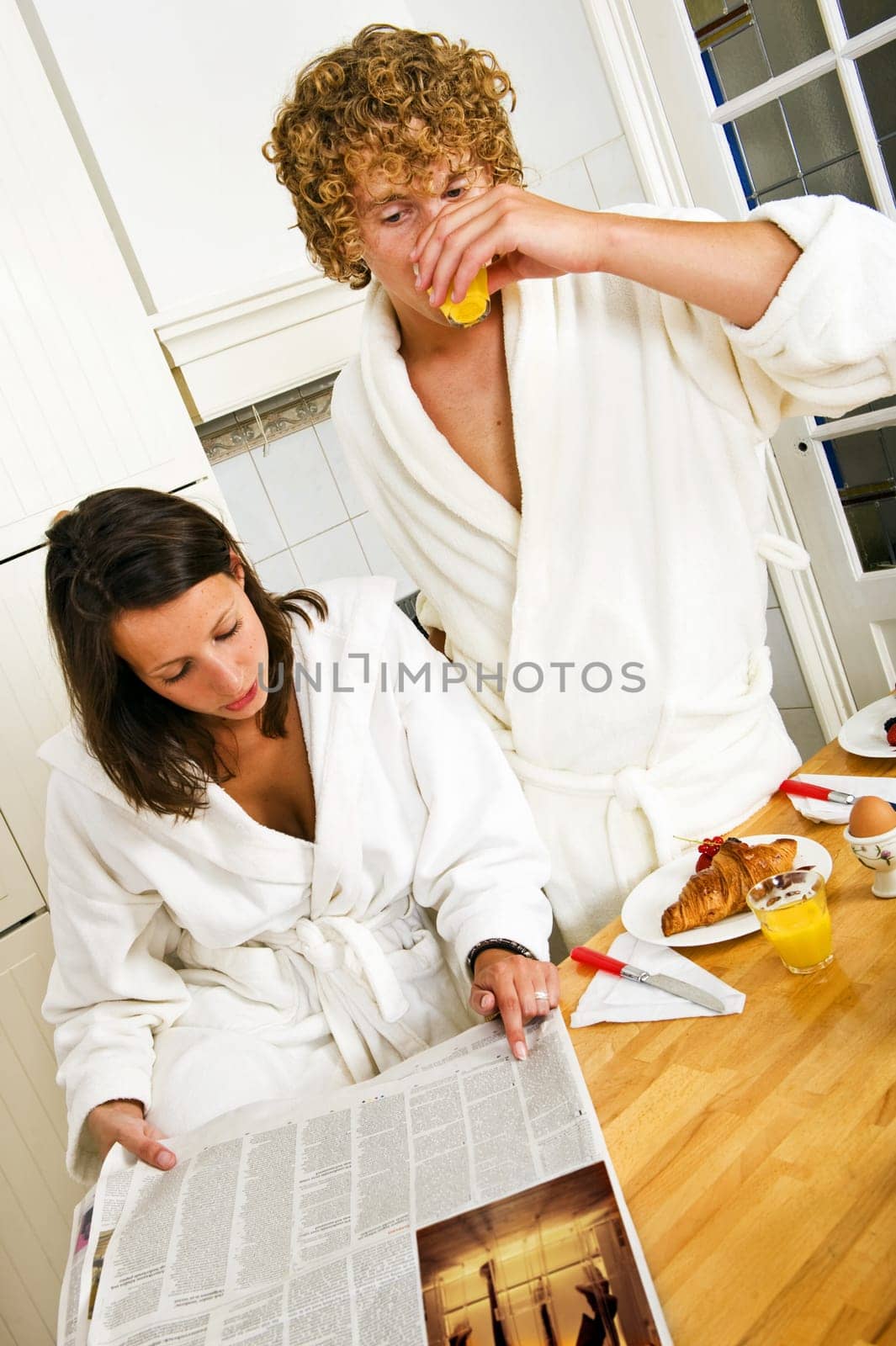 Young couple reading the paper on a casual morning breakfast in the kitchen