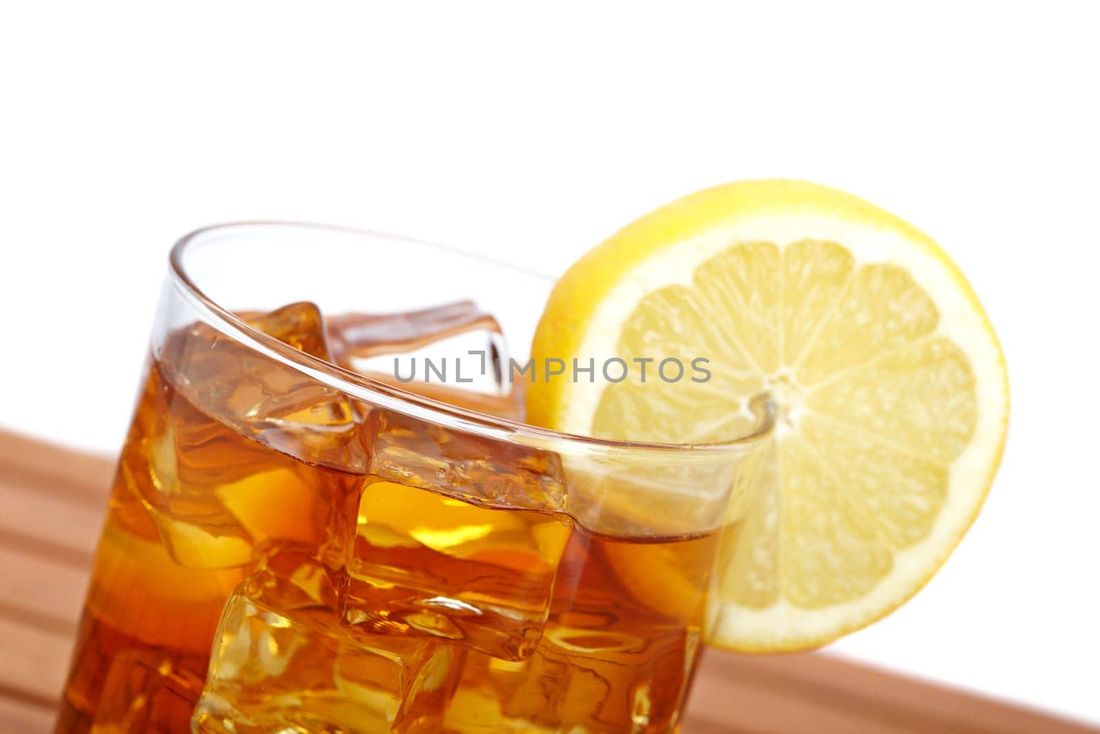 A glass of ice tea with lemon slice on wooden background. Shallow depth of field