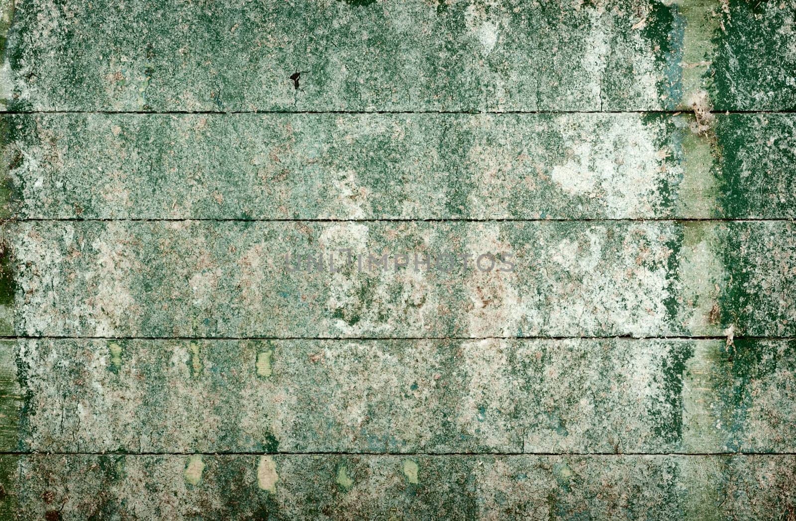Green messy surface of the old, semidecayed wall covered with boards