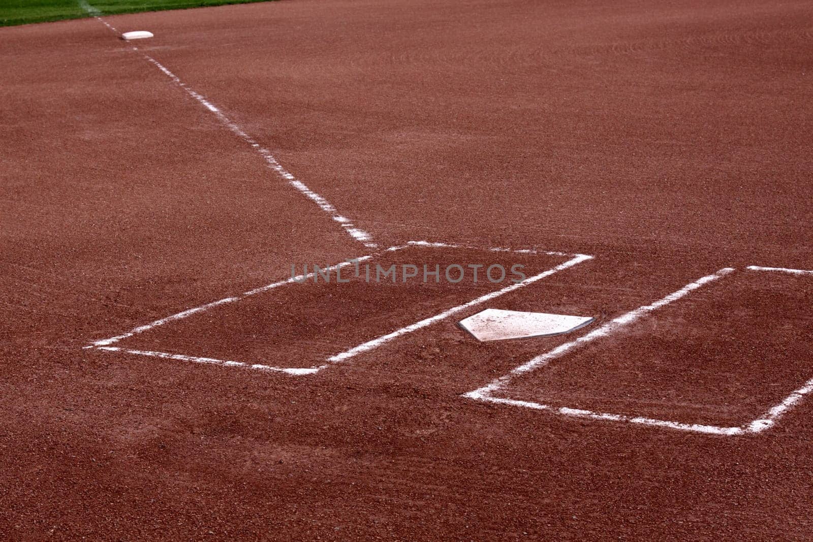 A close-up of the batters boxes and home plate on a vacant baseball diamond.