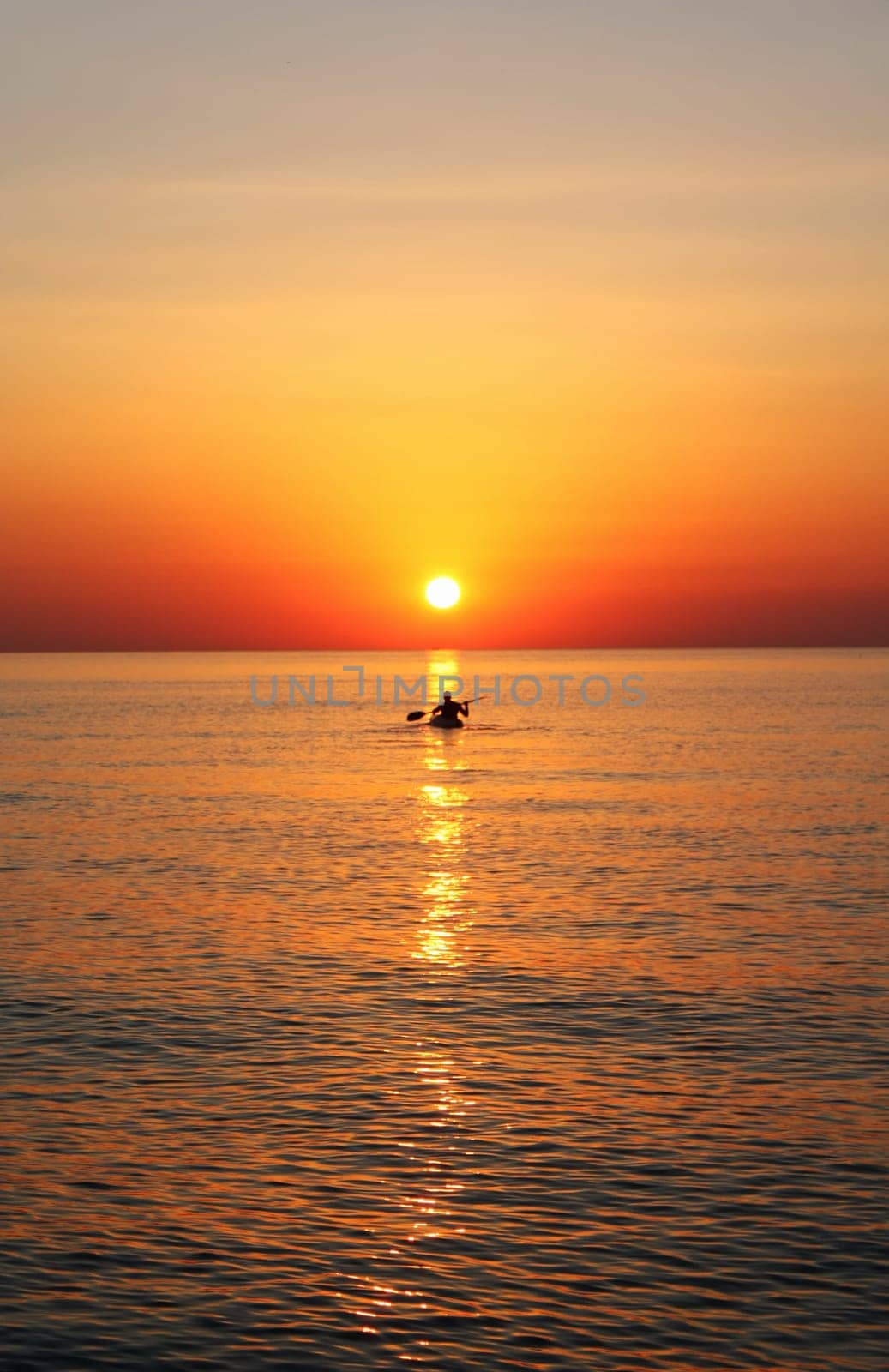 A man doing kayak at the sunrise on a calm sea