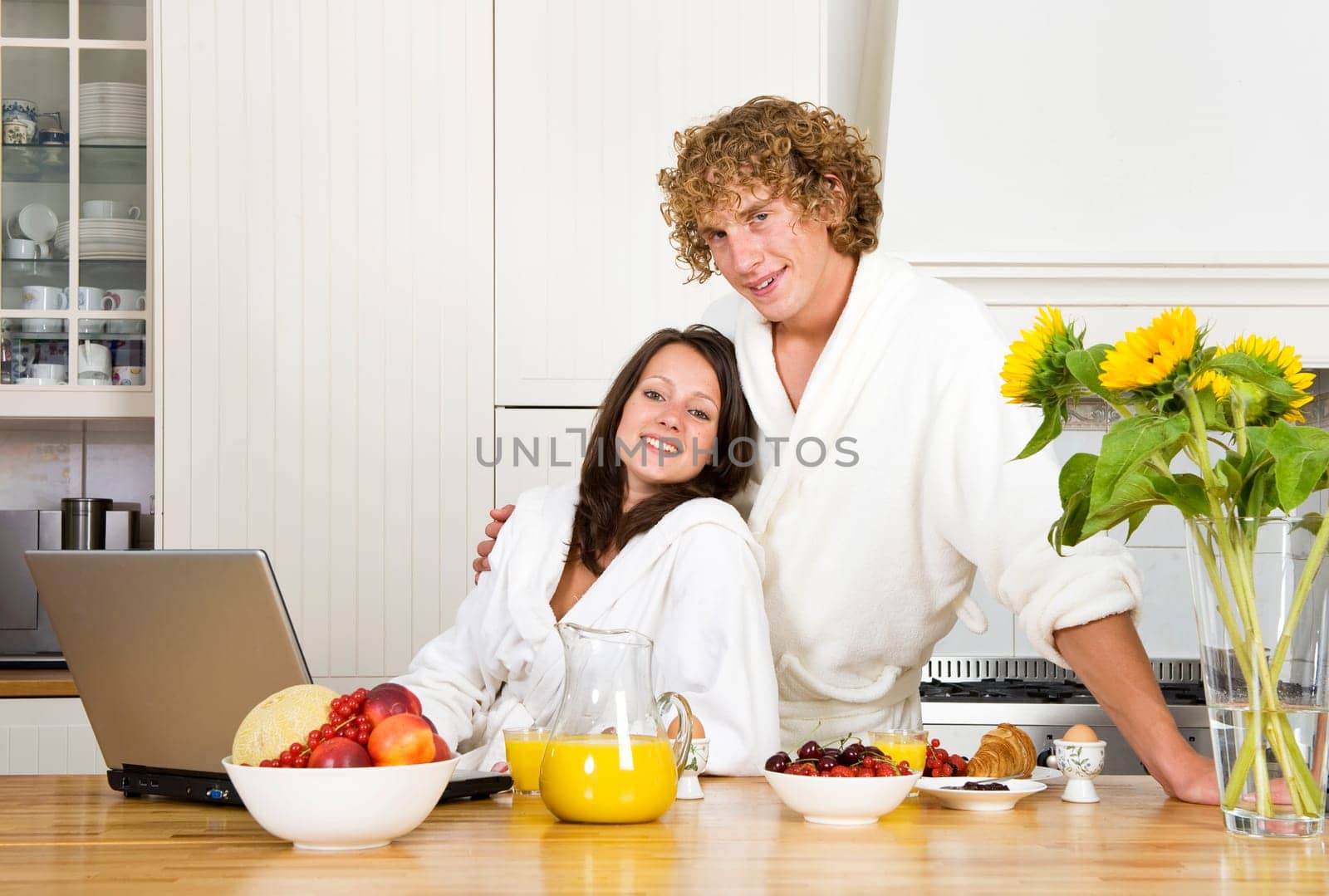 Young couple at breakfast, wearing bathrobes in a kitchen and looking at the camera