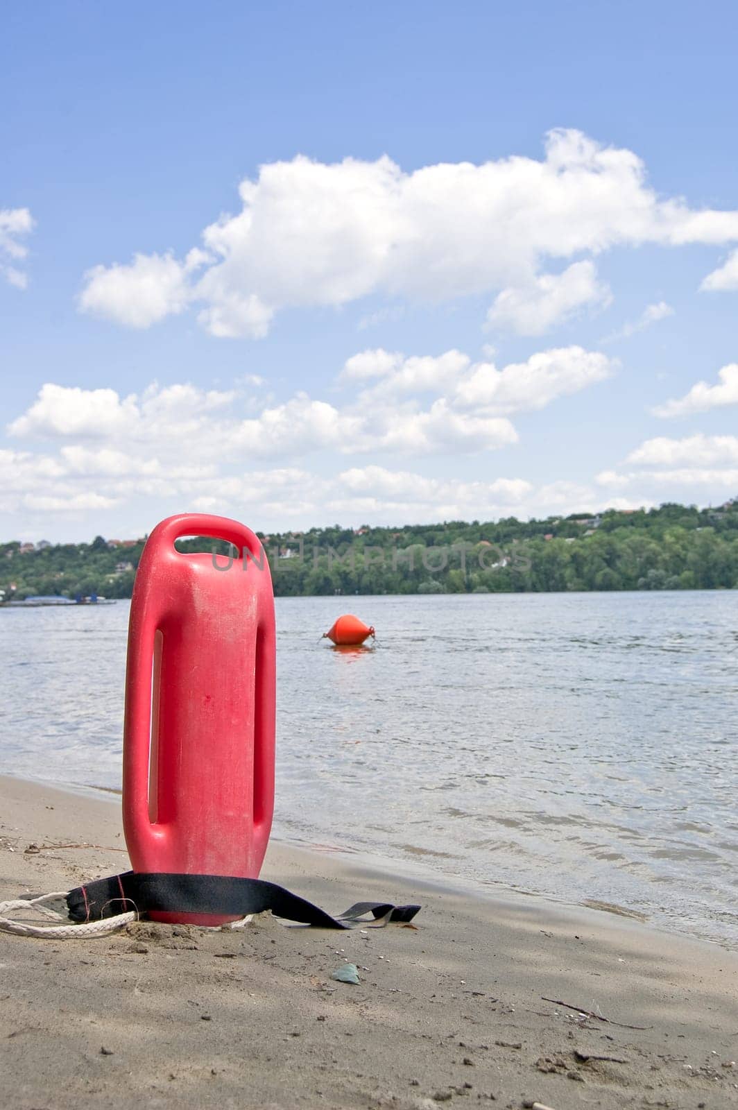 Lifeguard buoy in sand next to river