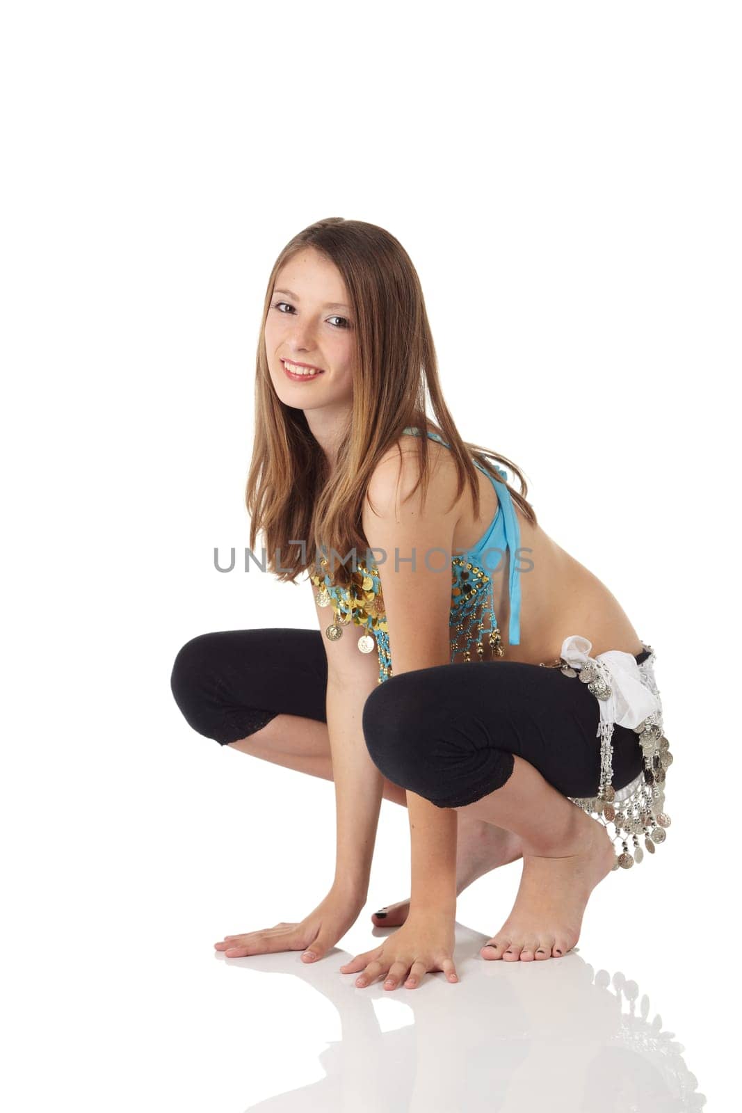 Young Caucasian belly dancing girl in beautiful decorated clothes on white background and reflective floor. Not isolated