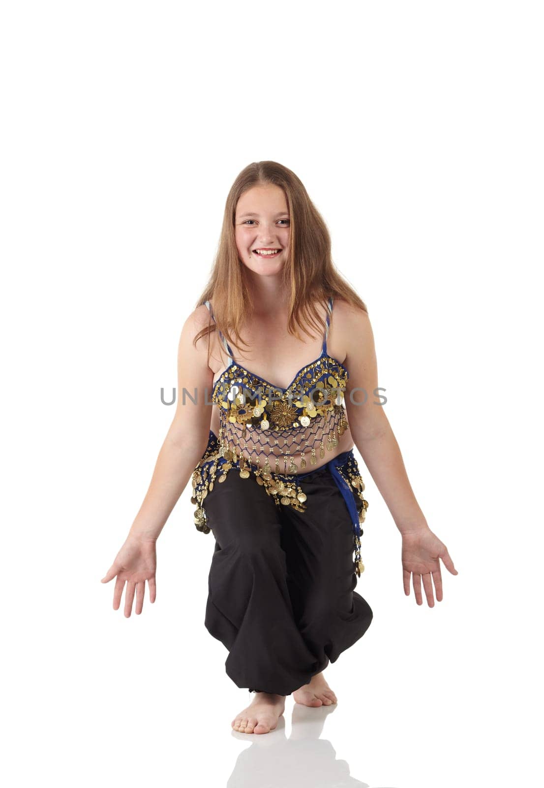 Young Caucasian belly dancing girl in beautiful decorated clothes on white background and reflective floor. Not isolated