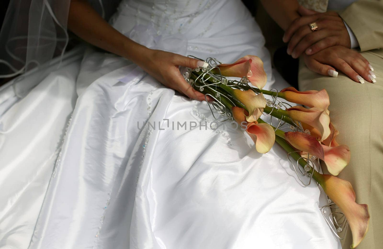 Bride holding colorful wedding bouquet, groom is sitting near