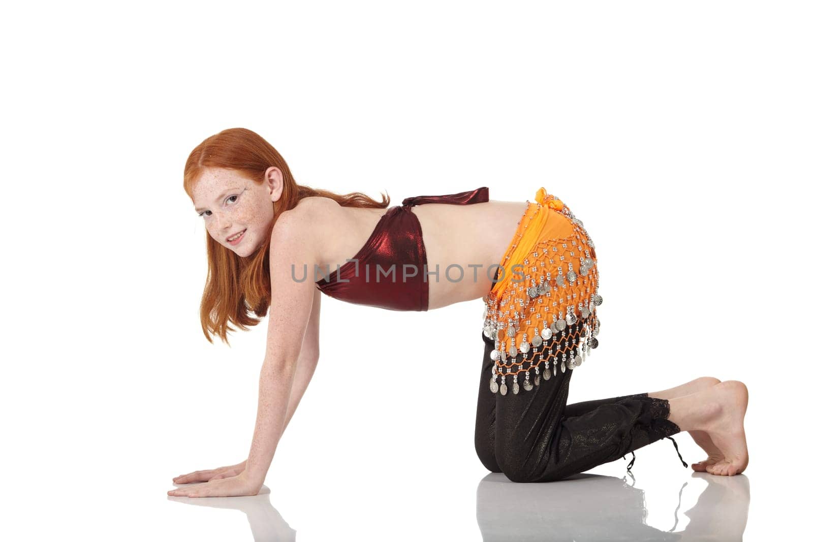 Young Caucasian belly dancing girl in beautiful decorated clothes on white background and reflective floor. Not isolated