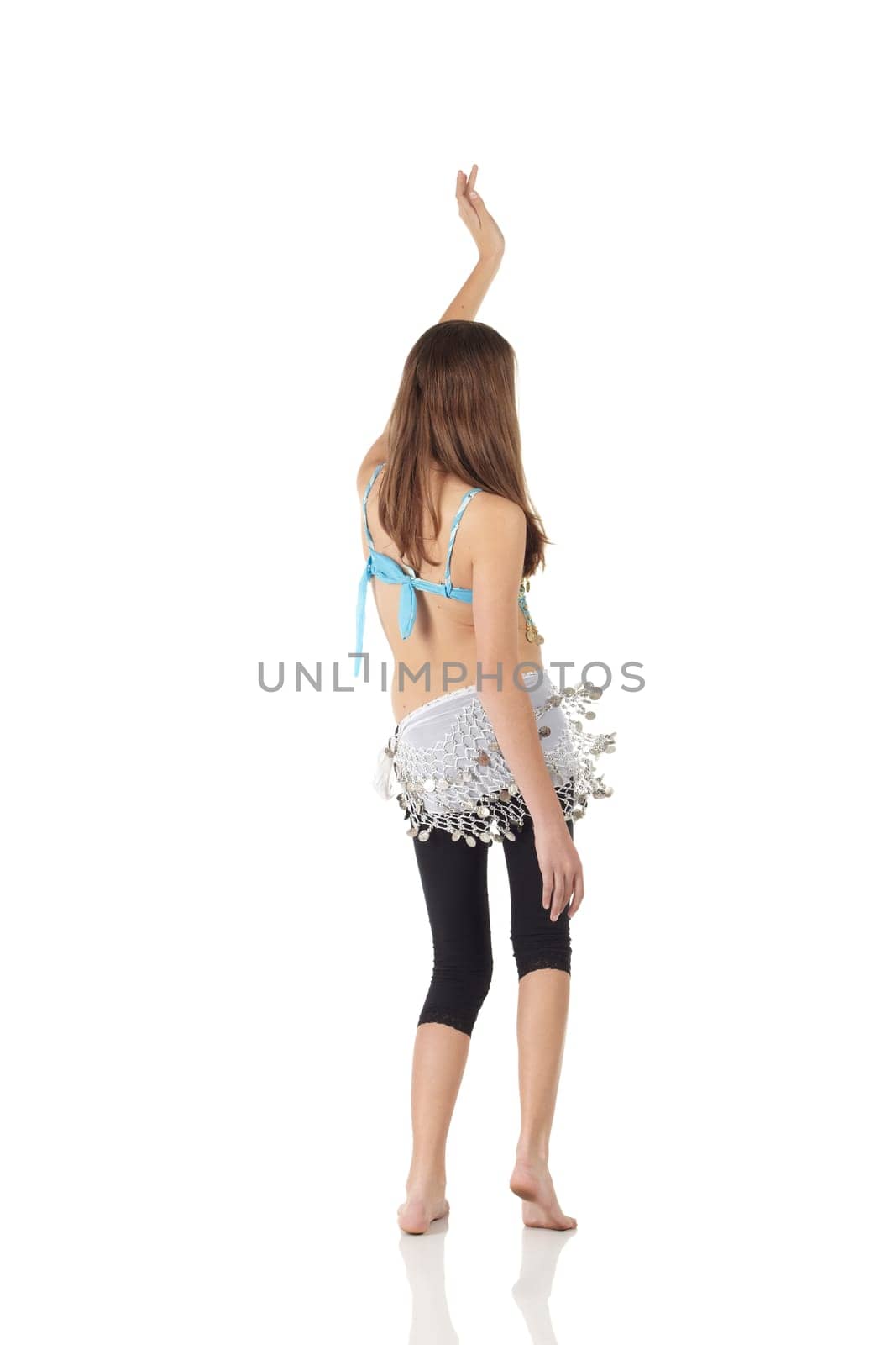 Young Caucasian belly dancing girl in beautiful decorated clothes on white background and reflective floor. Not isolated