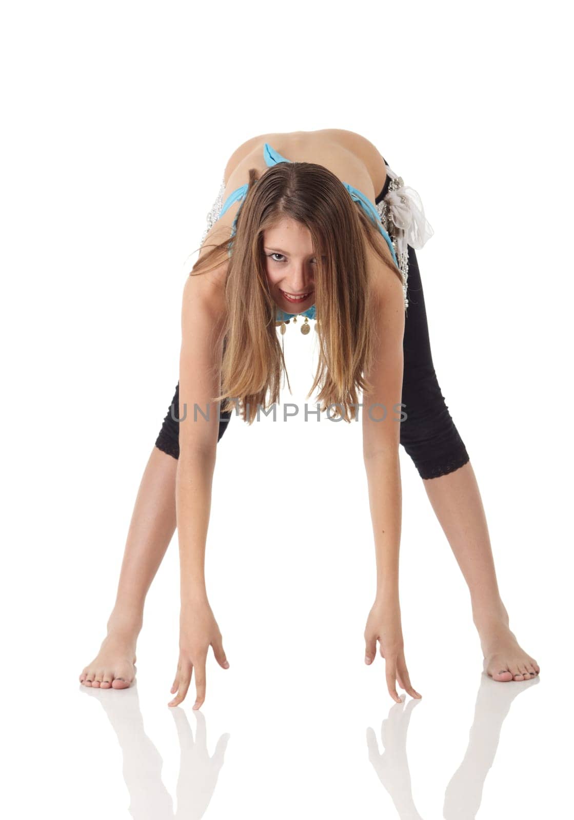 Young Caucasian belly dancing girl in beautiful decorated clothes on white background and reflective floor. Not isolated