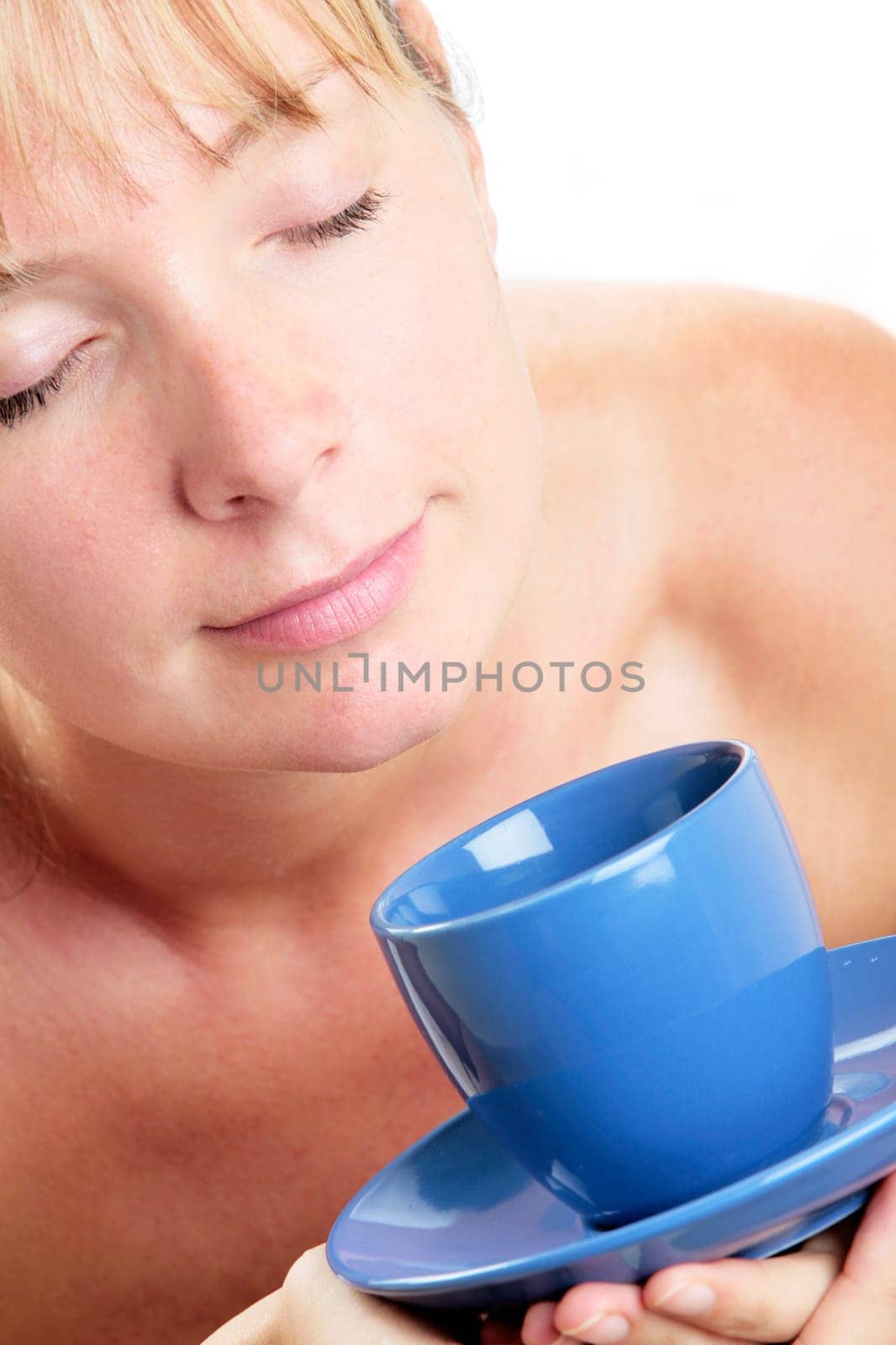 Woman in soft light drinking coffee from a blue cup and saucer