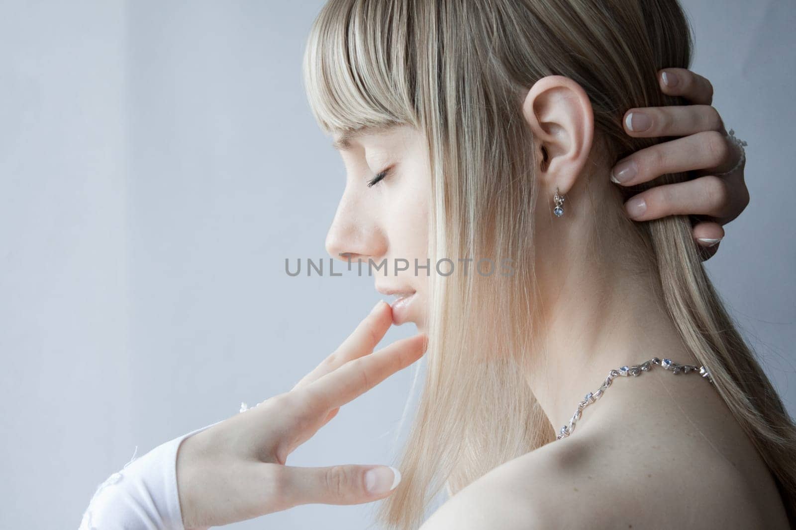 young blonde sexy girl posing with white gloves on her hands and her eyes closed