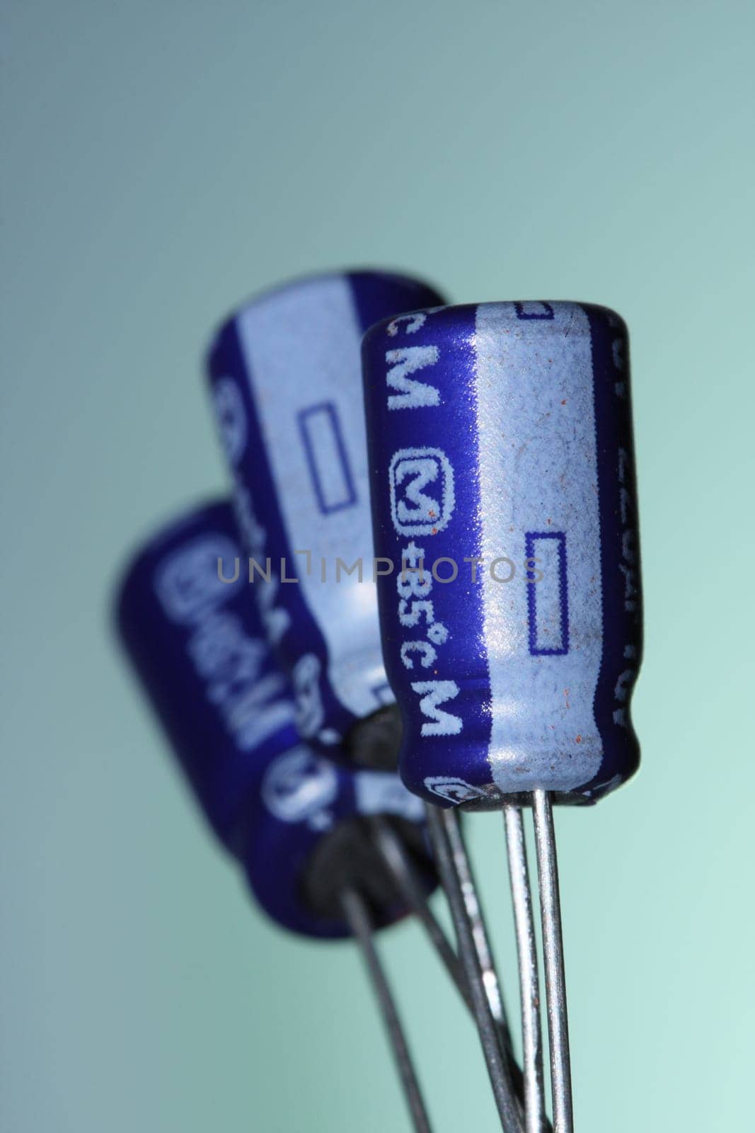 Three electrolytic capacitors on a blue background.