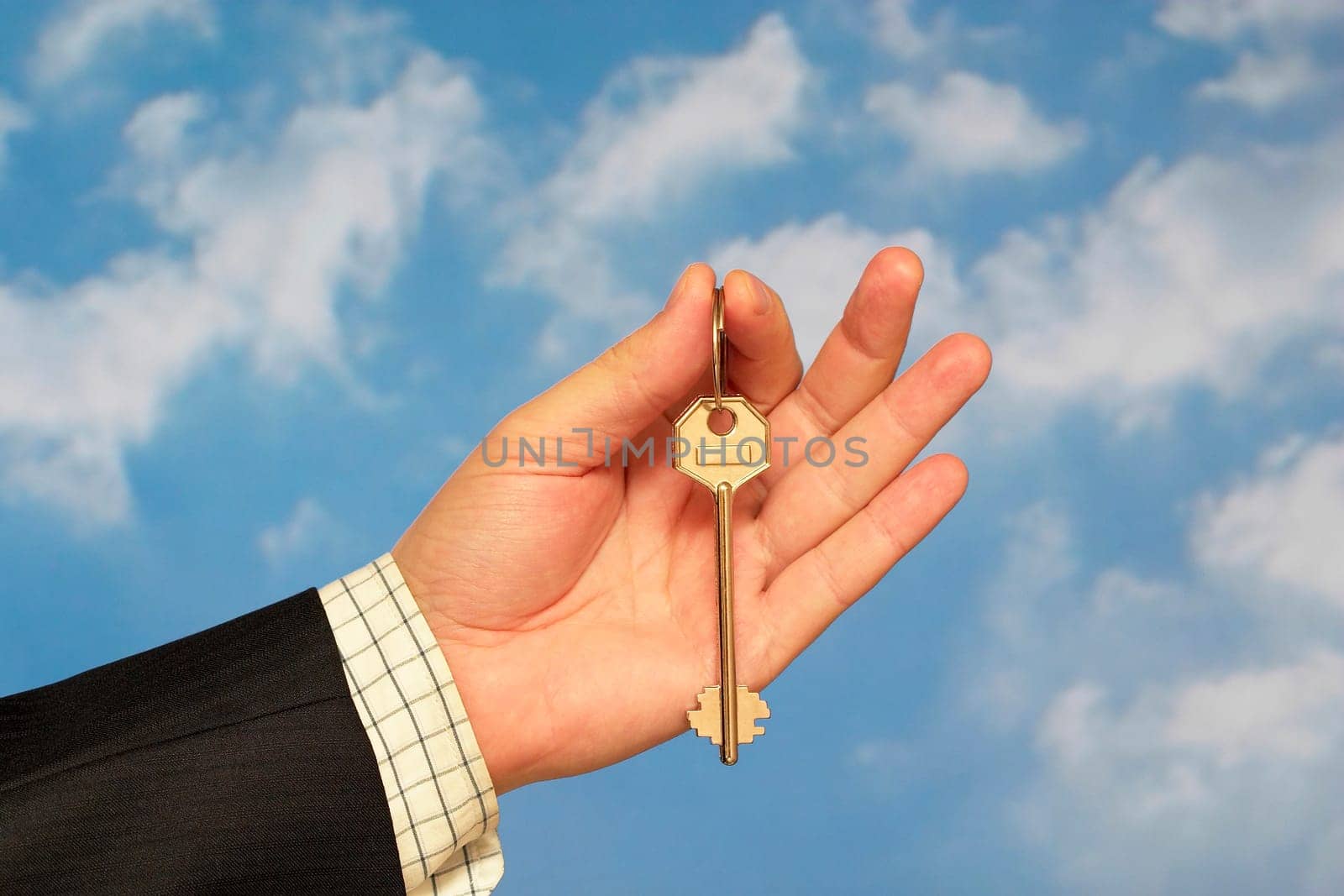 Hand holding a key over sky and clouds backgound