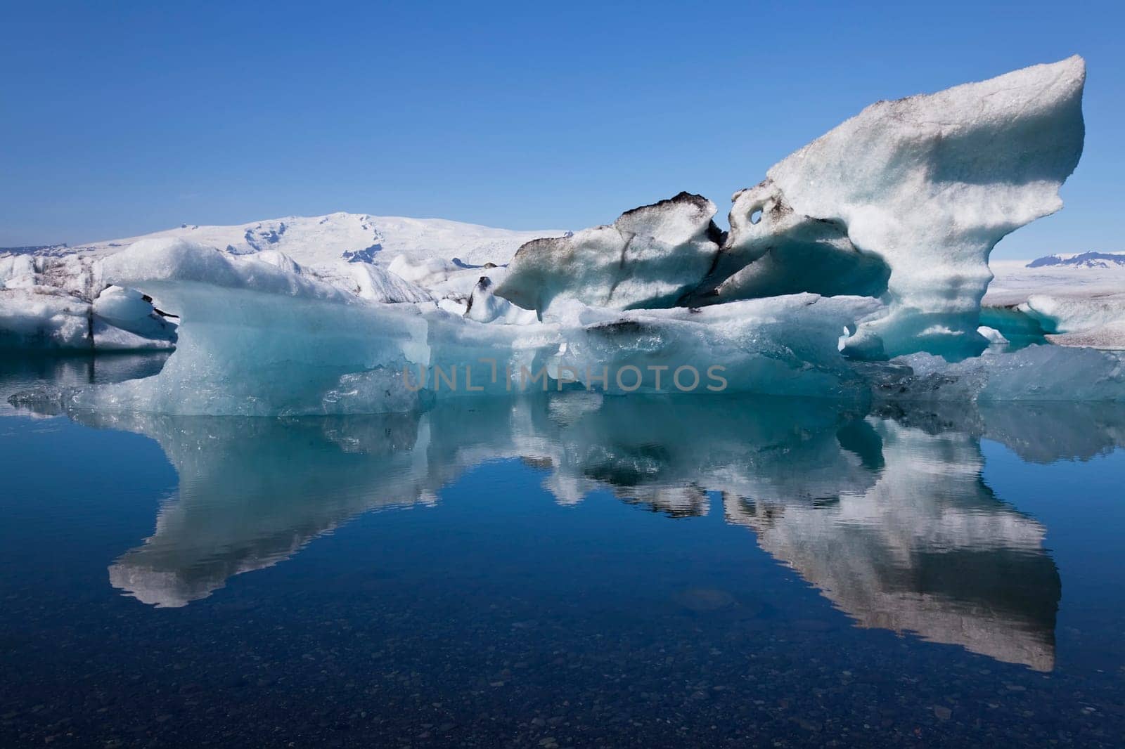 A glacial iceberg and its symmetrical reflection floating on the Iceberg Lagoon, Jokullsarlon, Iceland