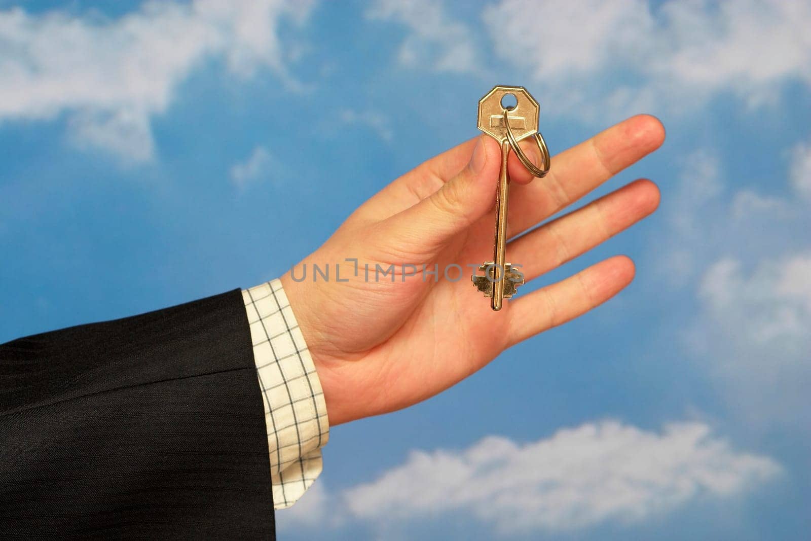 Hand holding a key over sky and clouds backgound