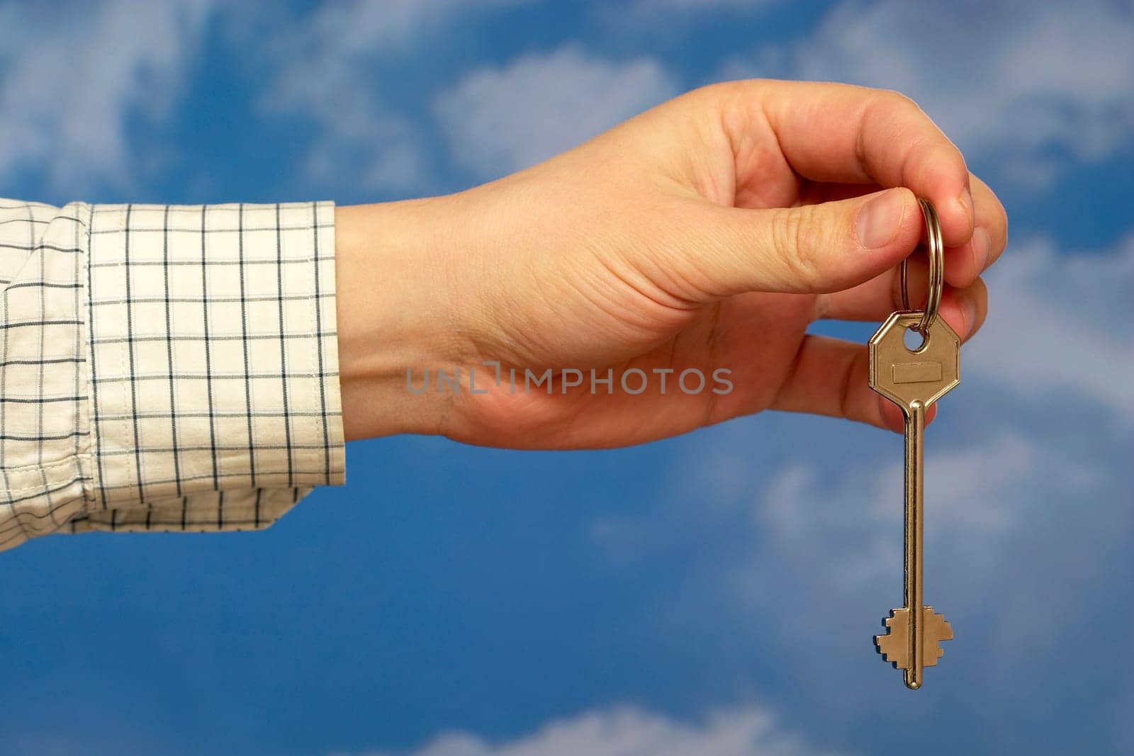Hand holding a key over sky and clouds backgound