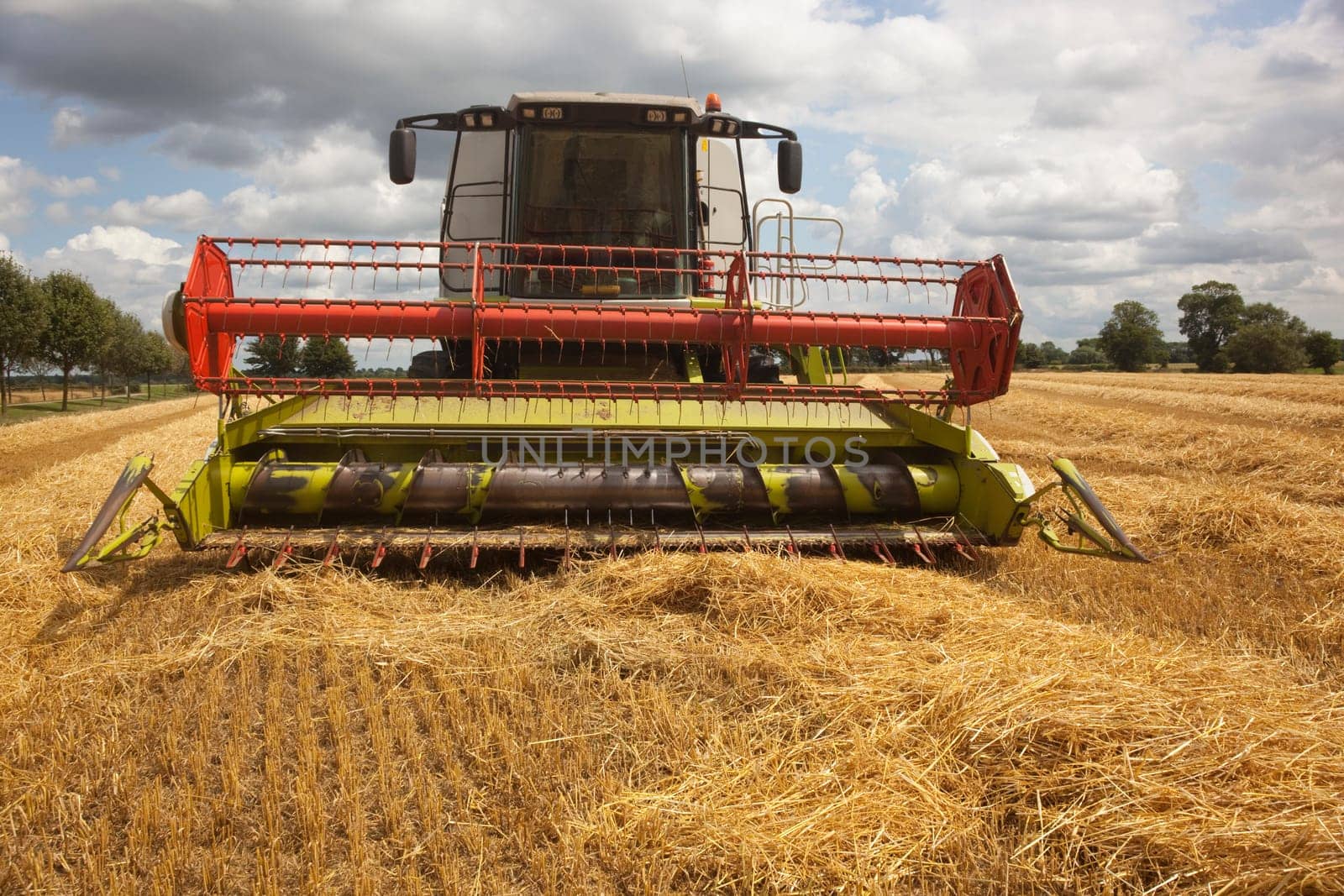 a combine harvester in a field of cut barley in summer
