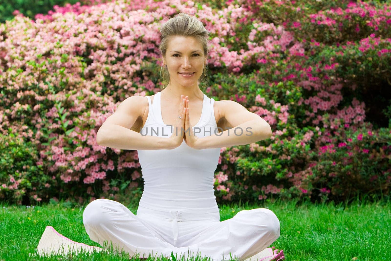 Blonde girl in nature green park exercising yoga, fitness program