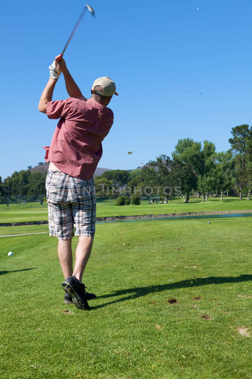 A Man golfing swinging his club toward the tee
