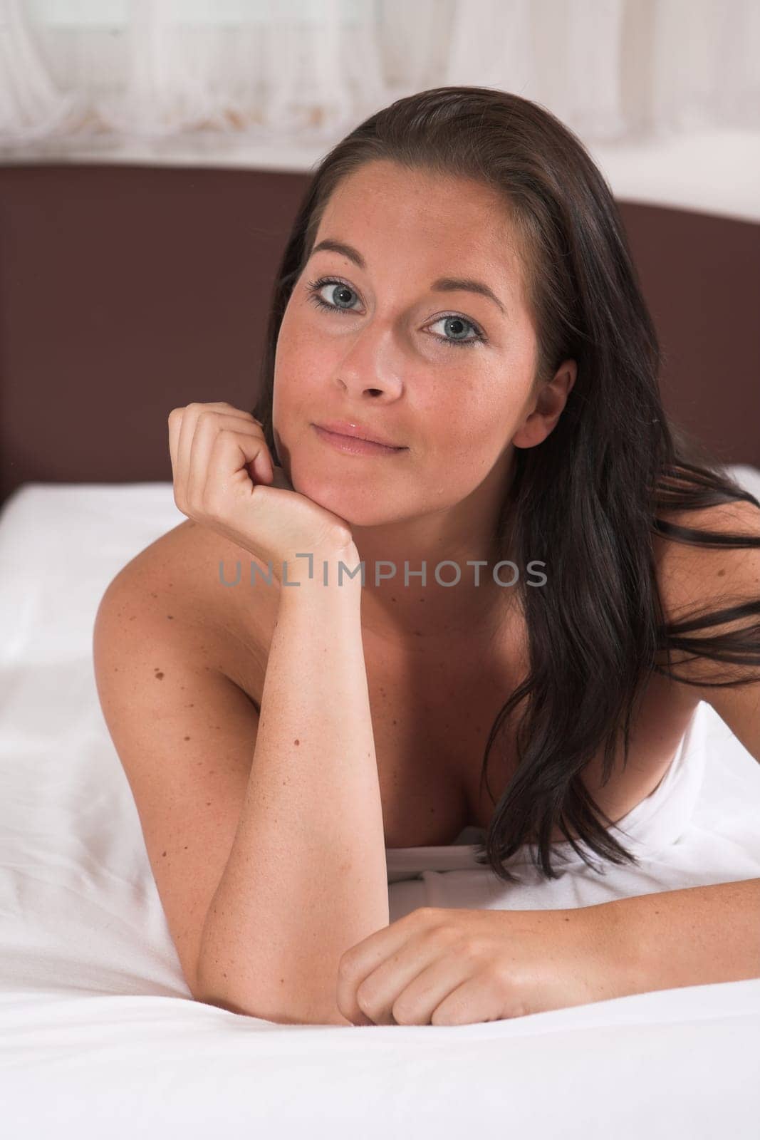Attractive Woman lies in her bad loonkig straight into camera