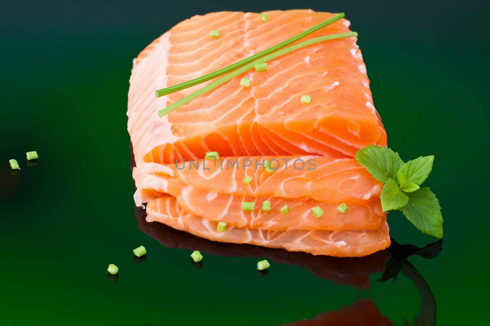 a piece of fresh raw salmon with basil leaves