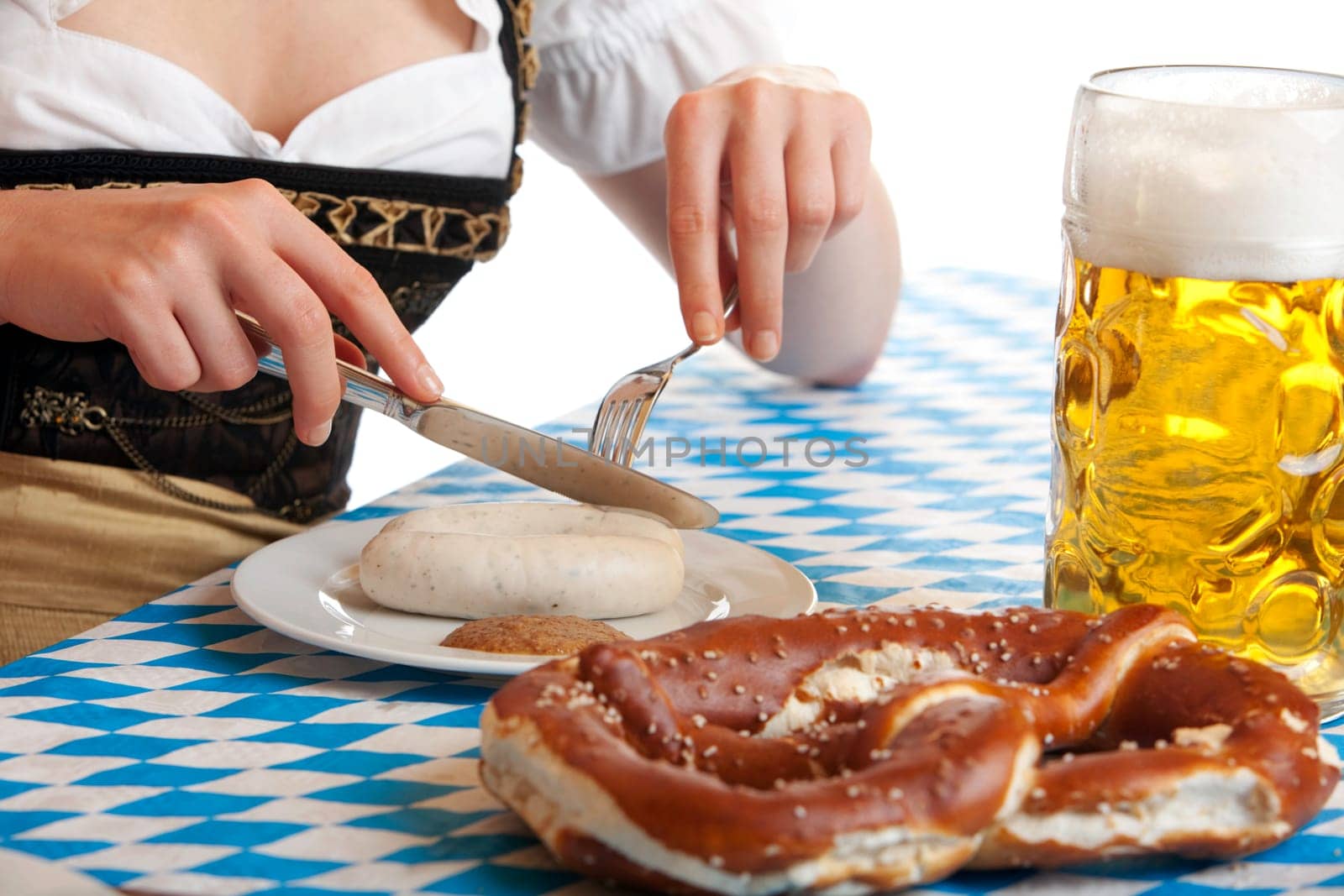 Close-up of Bavarian Girl having typical Oktoberfest meal with beer stein (Mass), sausage (Weisswurst) and Pretzel
