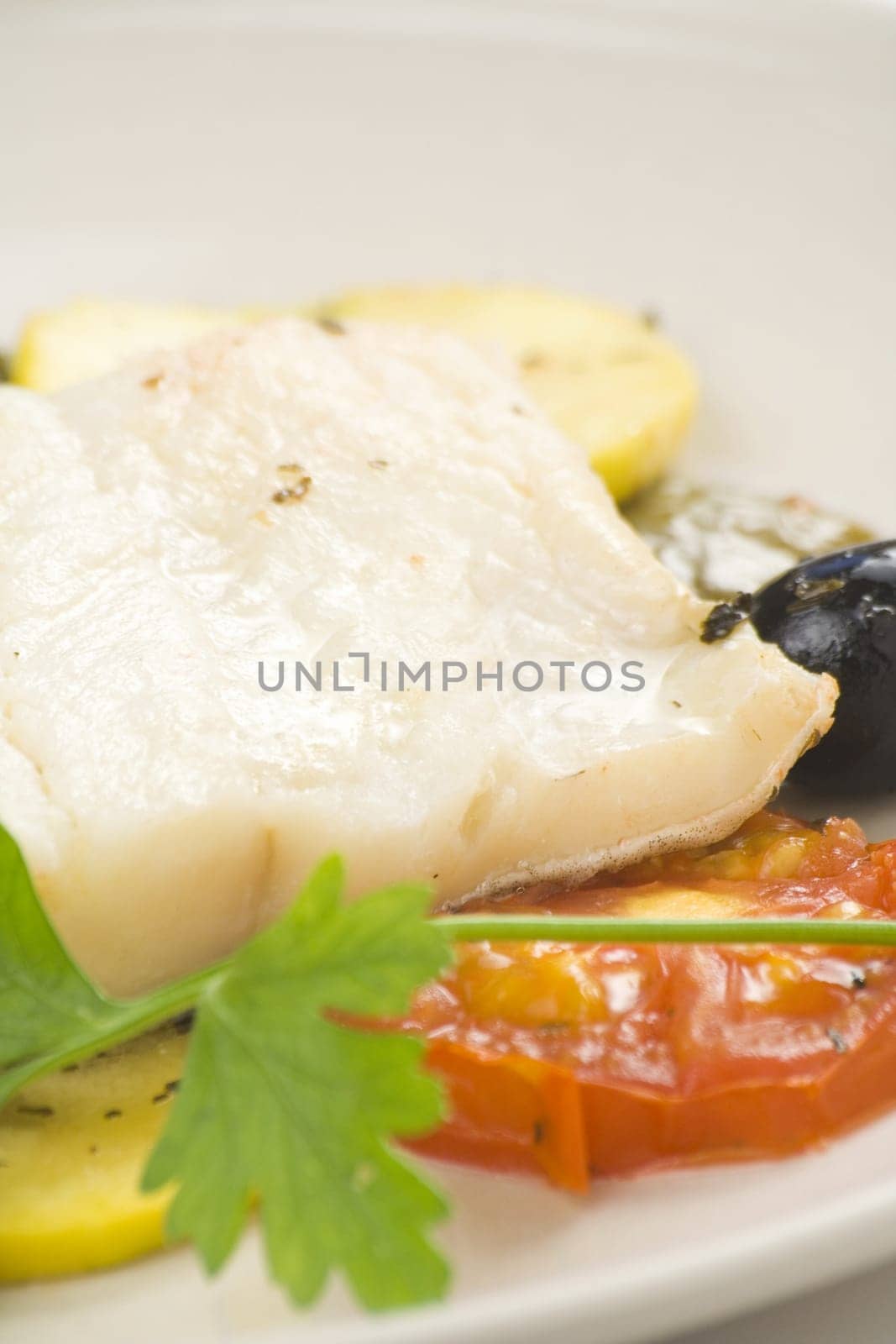 fillet of cod baked tomatoes zucchini black olives isolated