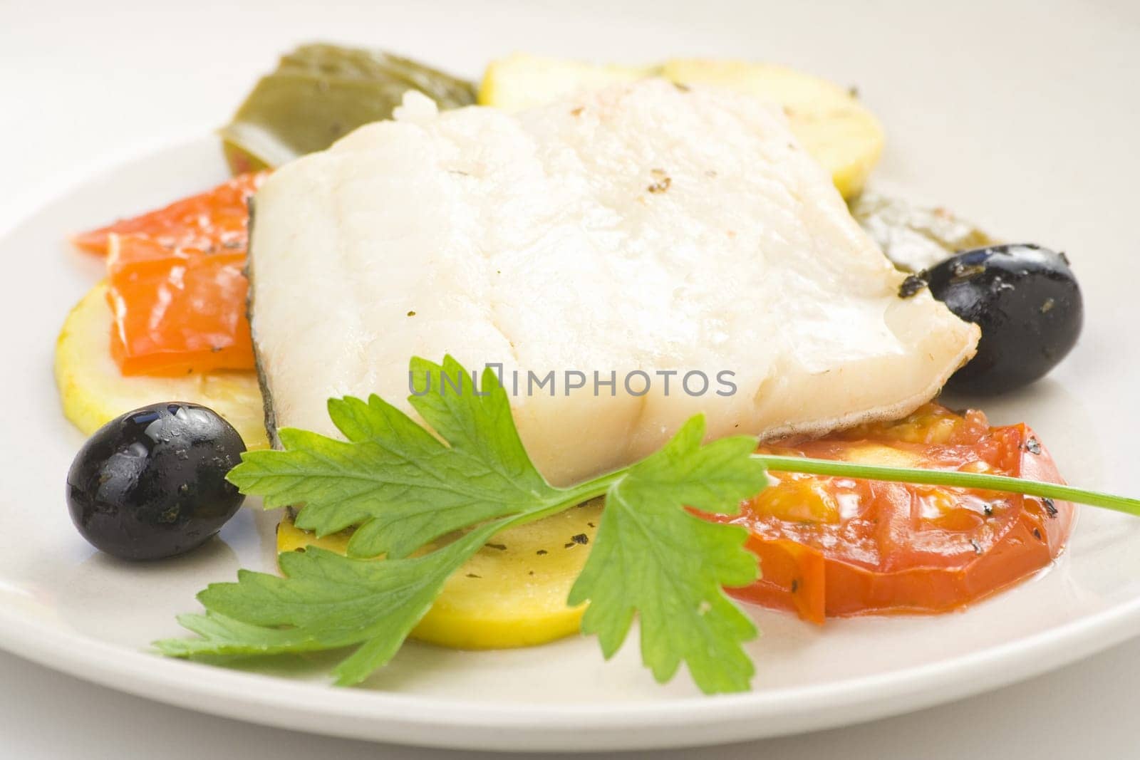 fillet of cod baked tomatoes zucchini black olives isolated