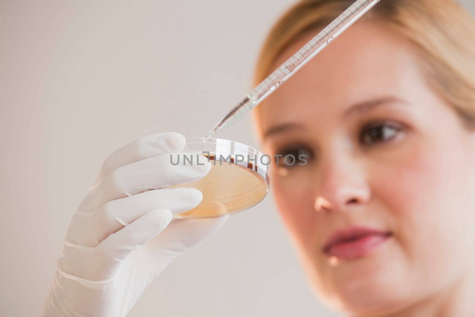 female scientist with dropper and petri dish